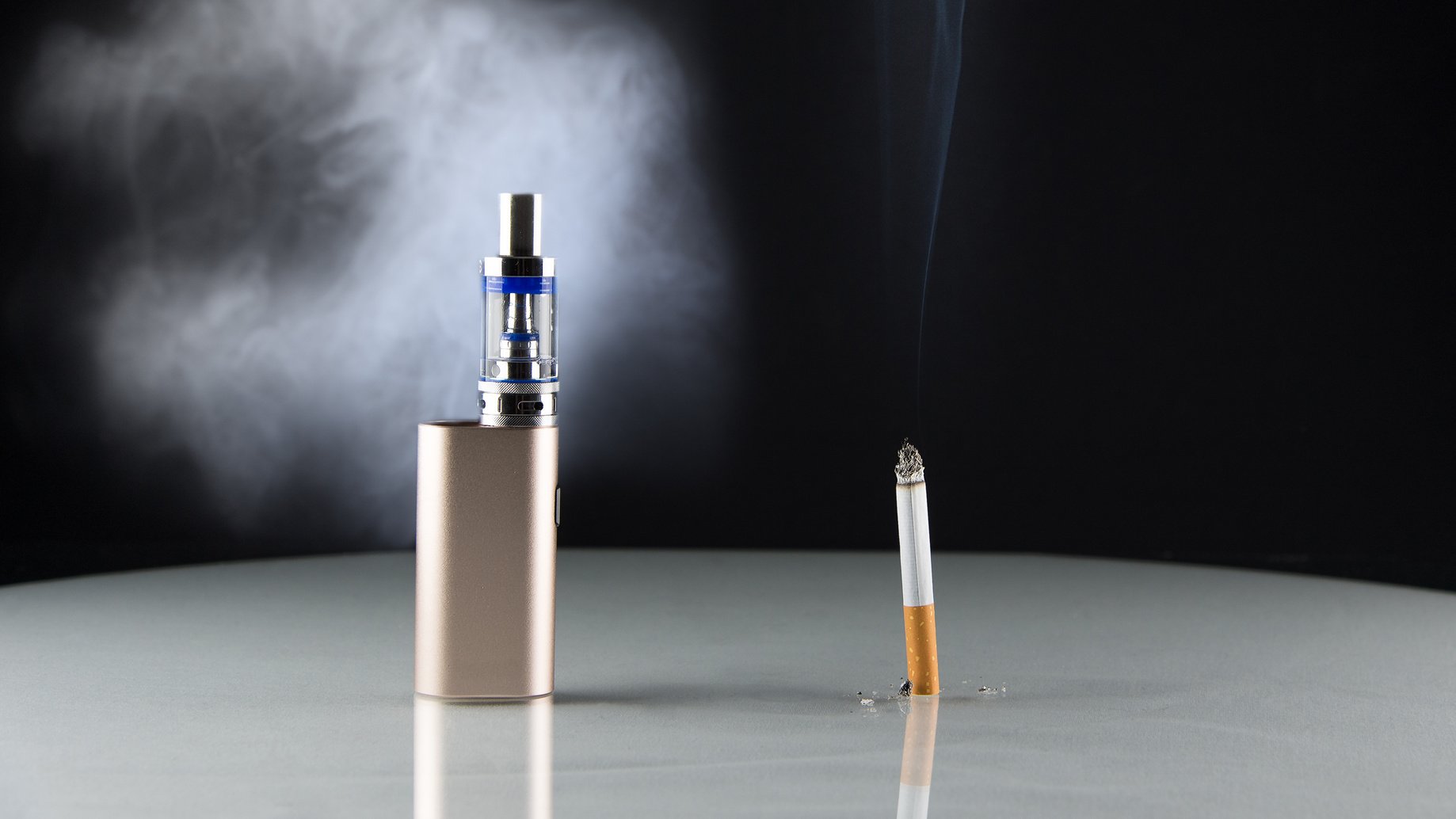 E-Zigarette und Tabakzigarette vor schwarzem Hintergrund